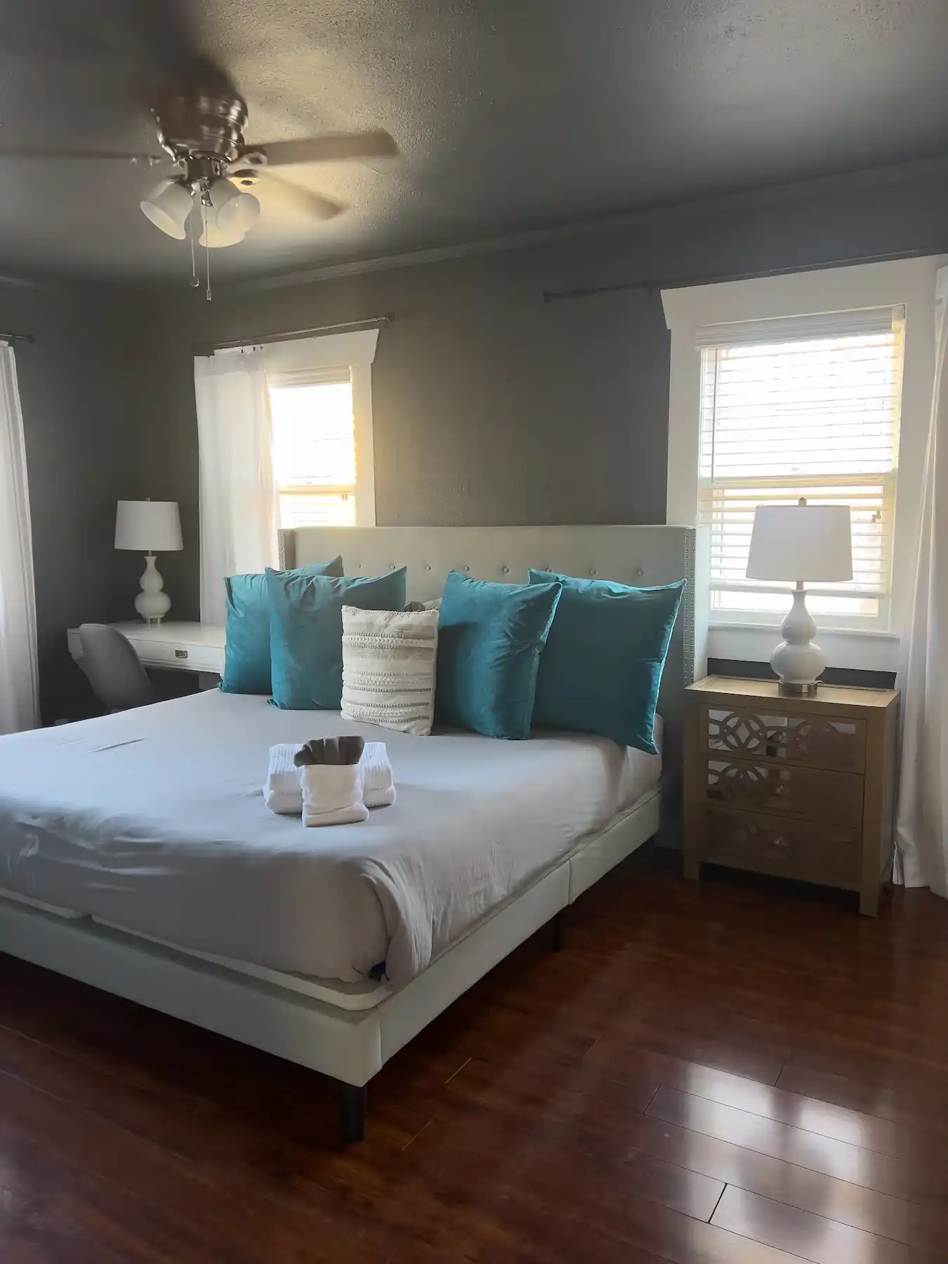 Big bed with colorful pillows, night stands, lamps, ceiling fan and folded bath towels