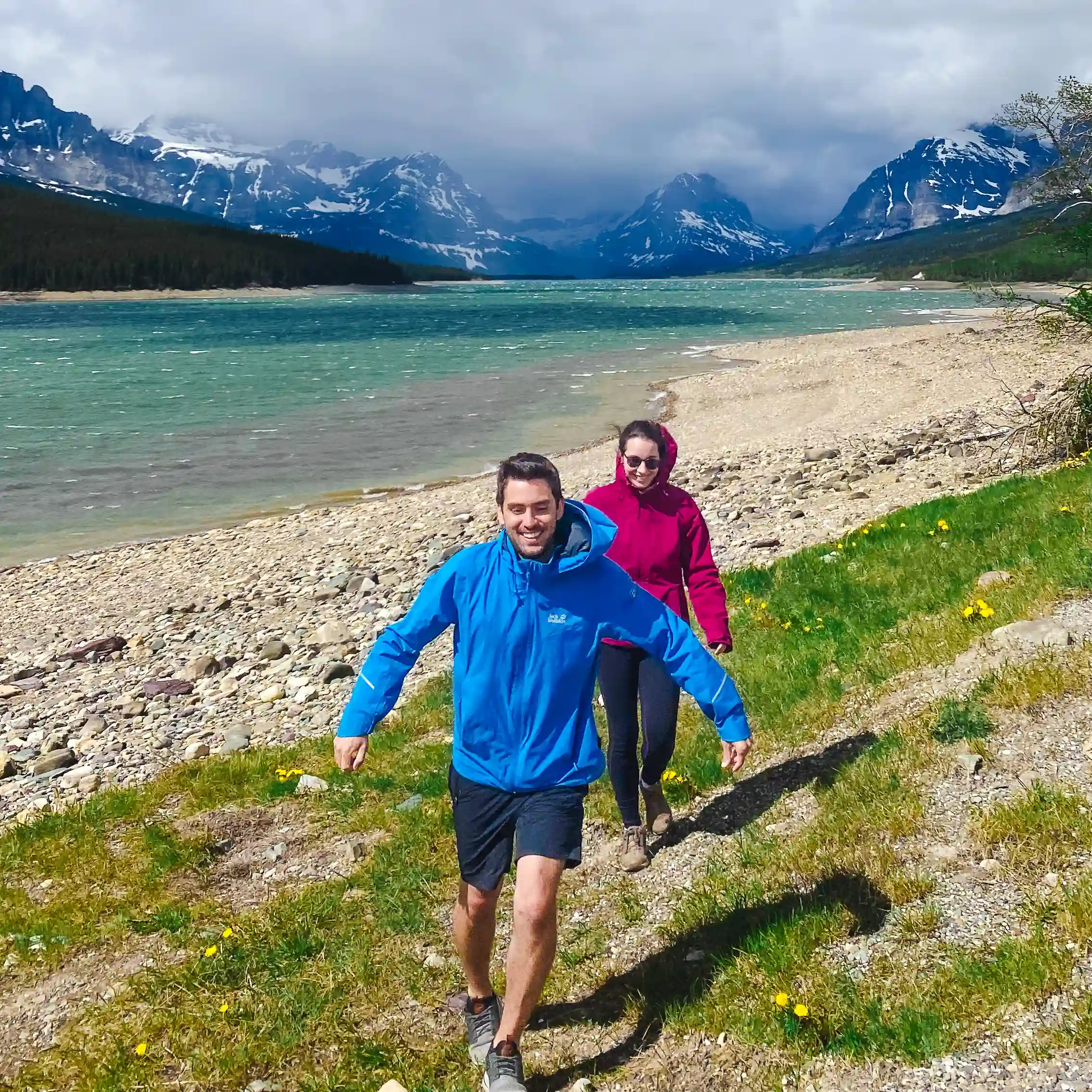 Man and woman playfully struggle against the wind in East Glacier National Park in Montana