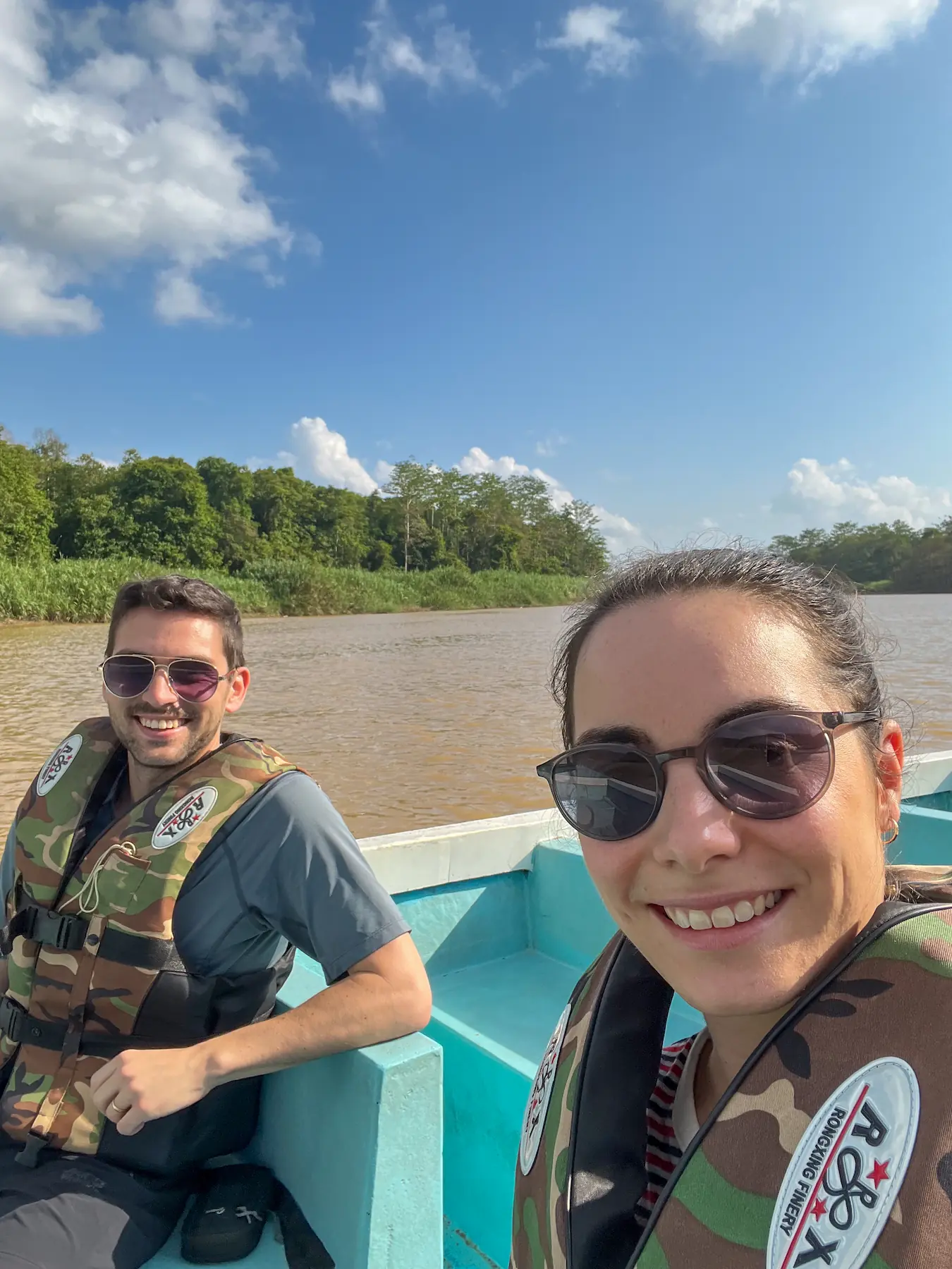 Man and woman wearing life jackets sitting in a boat on the Kinabatangan River in Borneo