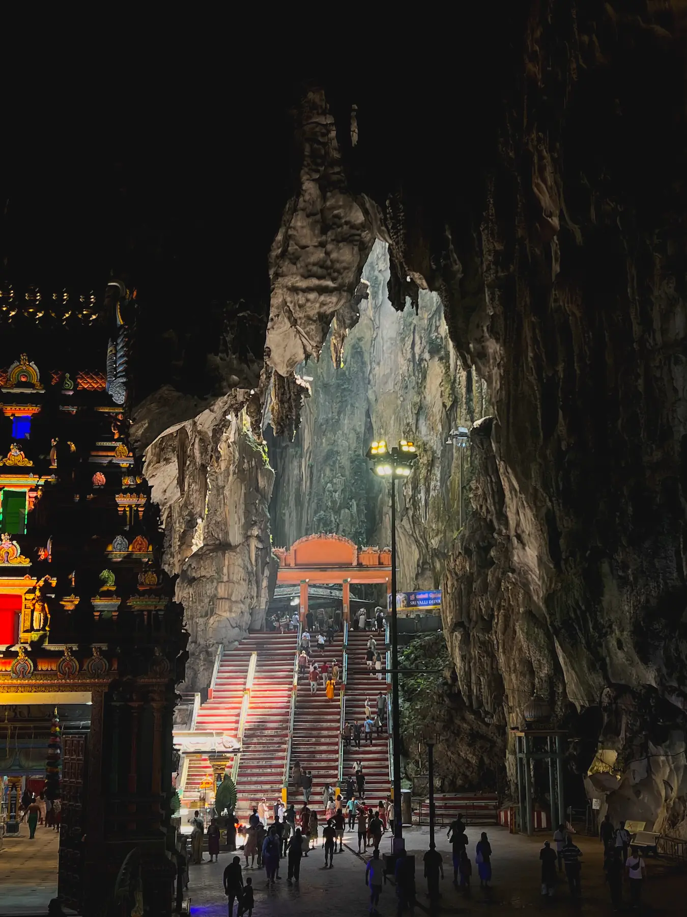 Inside of Batu Caves with sunlight shining through opening in ceiling